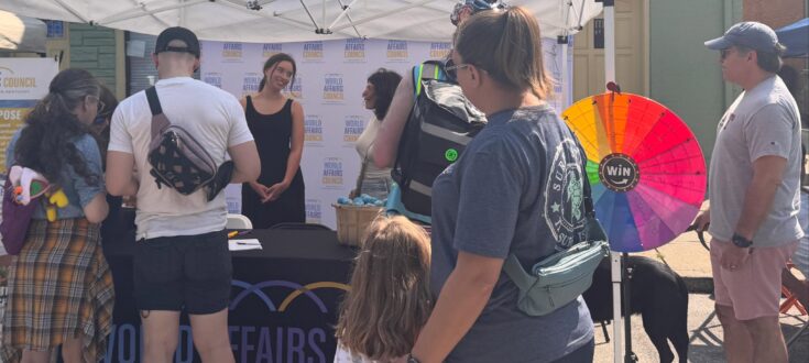 World Affairs Council booth at the Covington Farmers Market with staff happily talking to attendees. World Affairs Council booth at the Covington Farmers Market with staff happily talking to attendees.